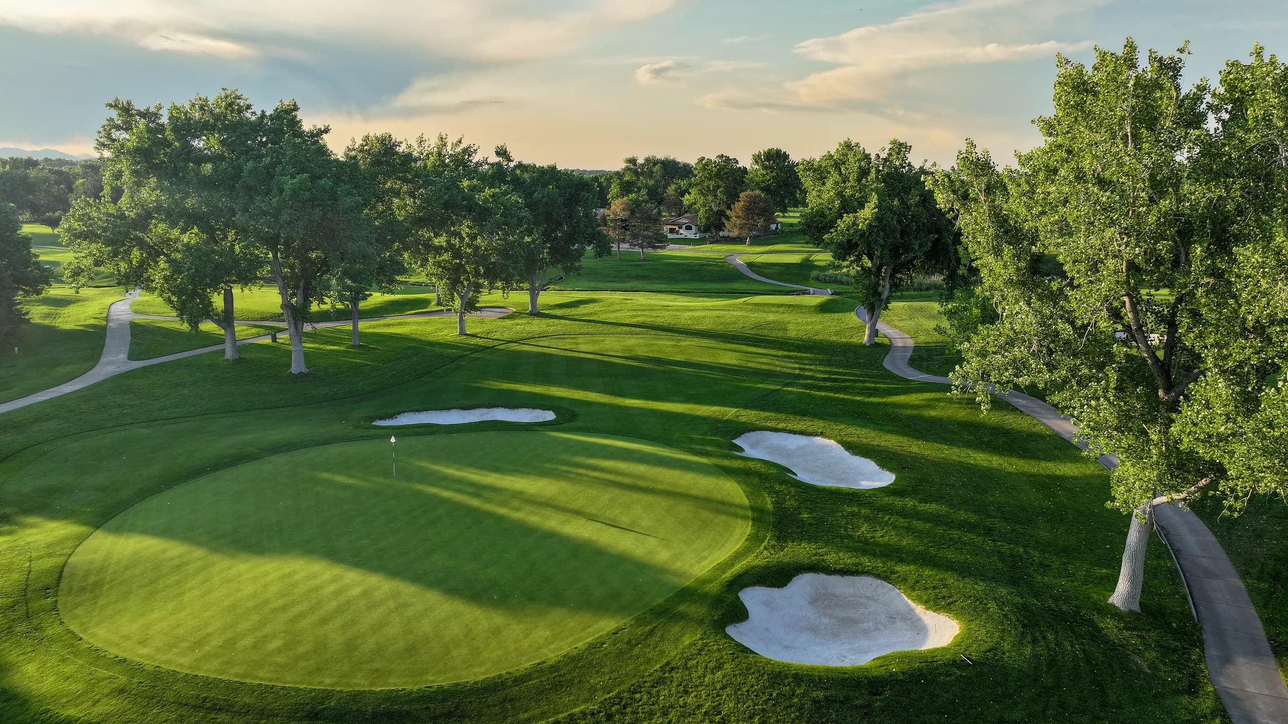 Parkland green with white bunkers and long evening tree shadows