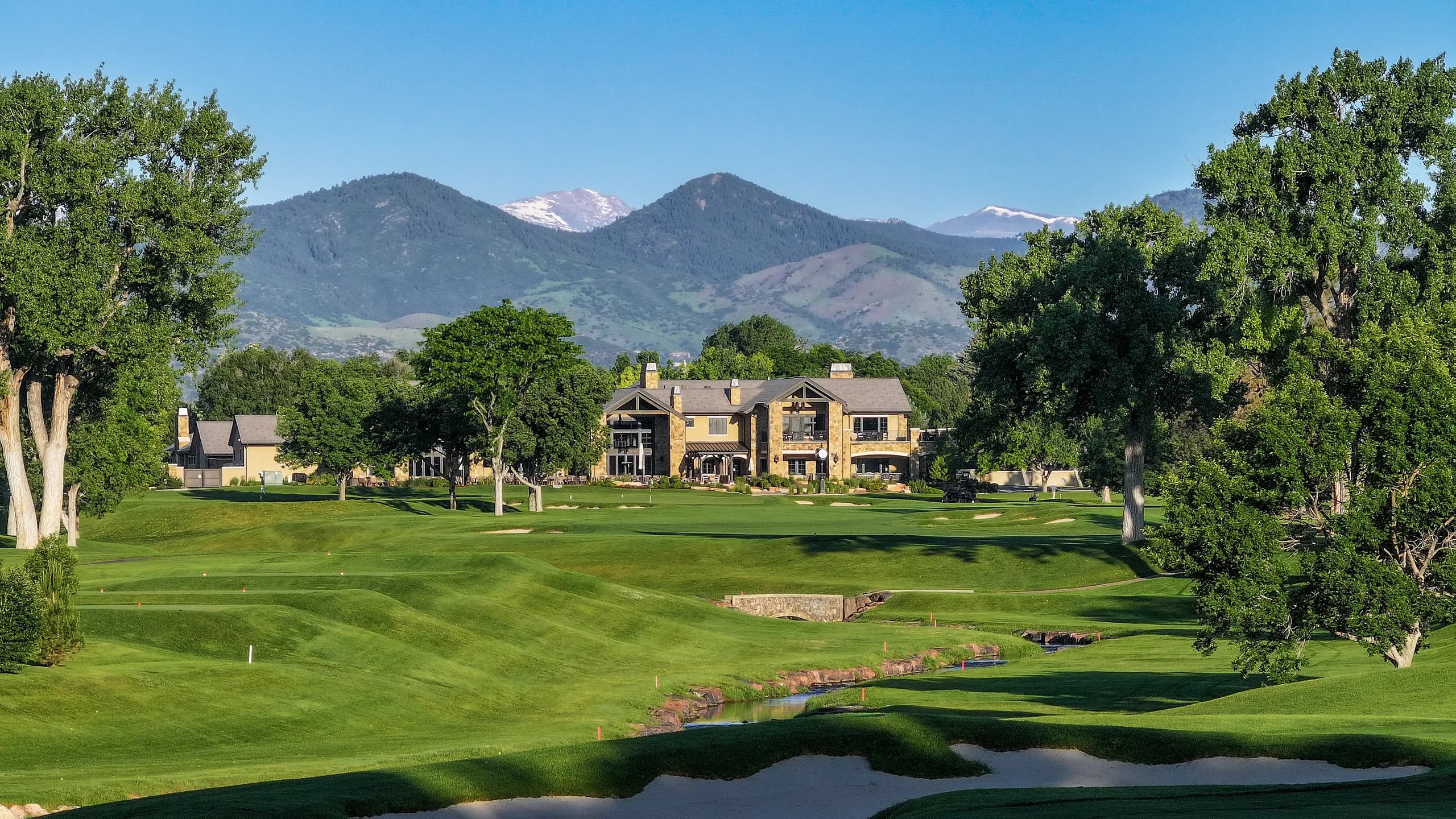 Stone clubhouse with snow-capped mountains behind it at a partner club